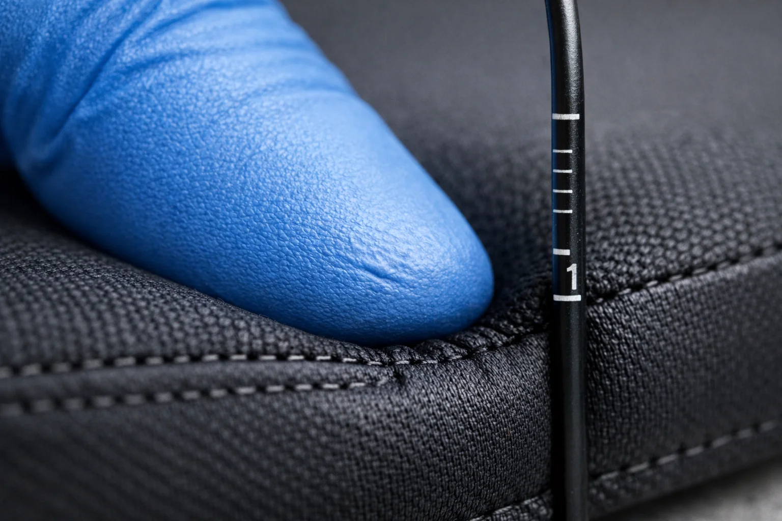 Close-up of a fingertip press test and depth probe indicating how soon a hard base is felt under a cushion