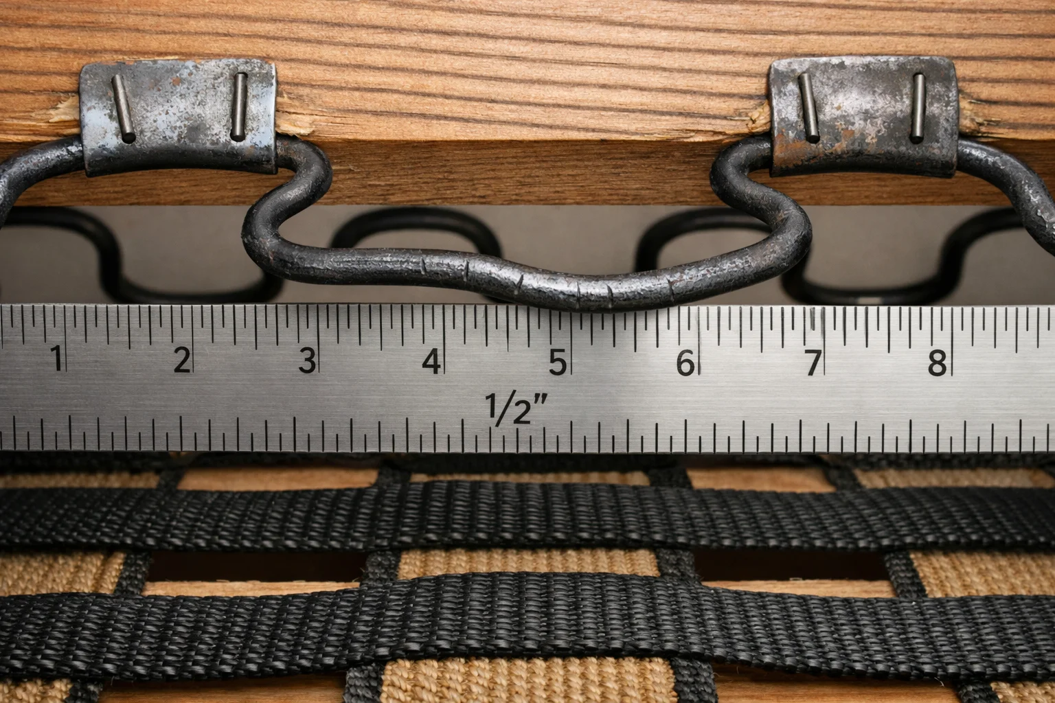 Close-up of sofa suspension with sinuous springs and webbing showing sag and wear at the clips
