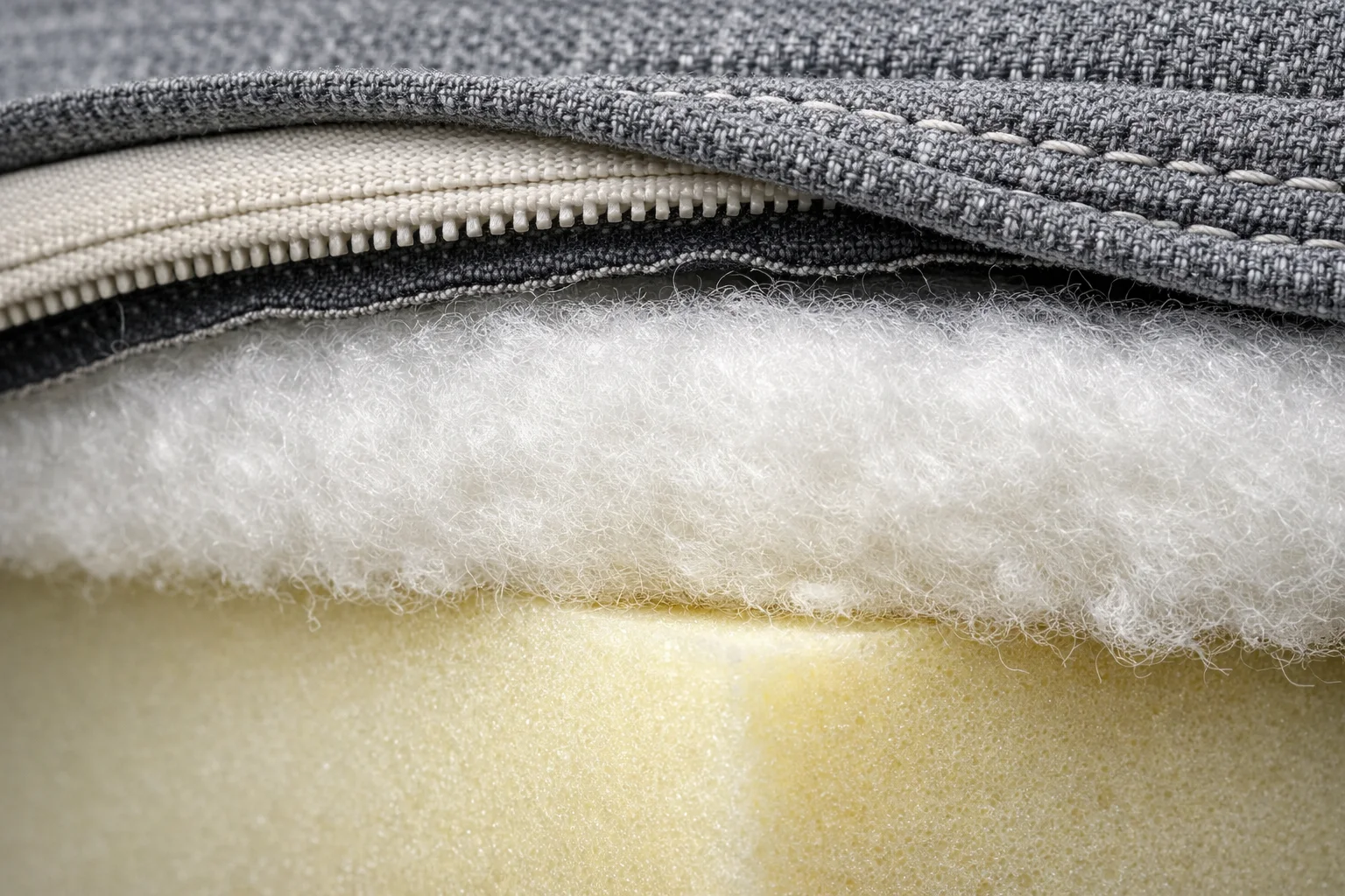 Close-up of cushion edge construction showing a distinct fluffy batting layer separate from the foam insert