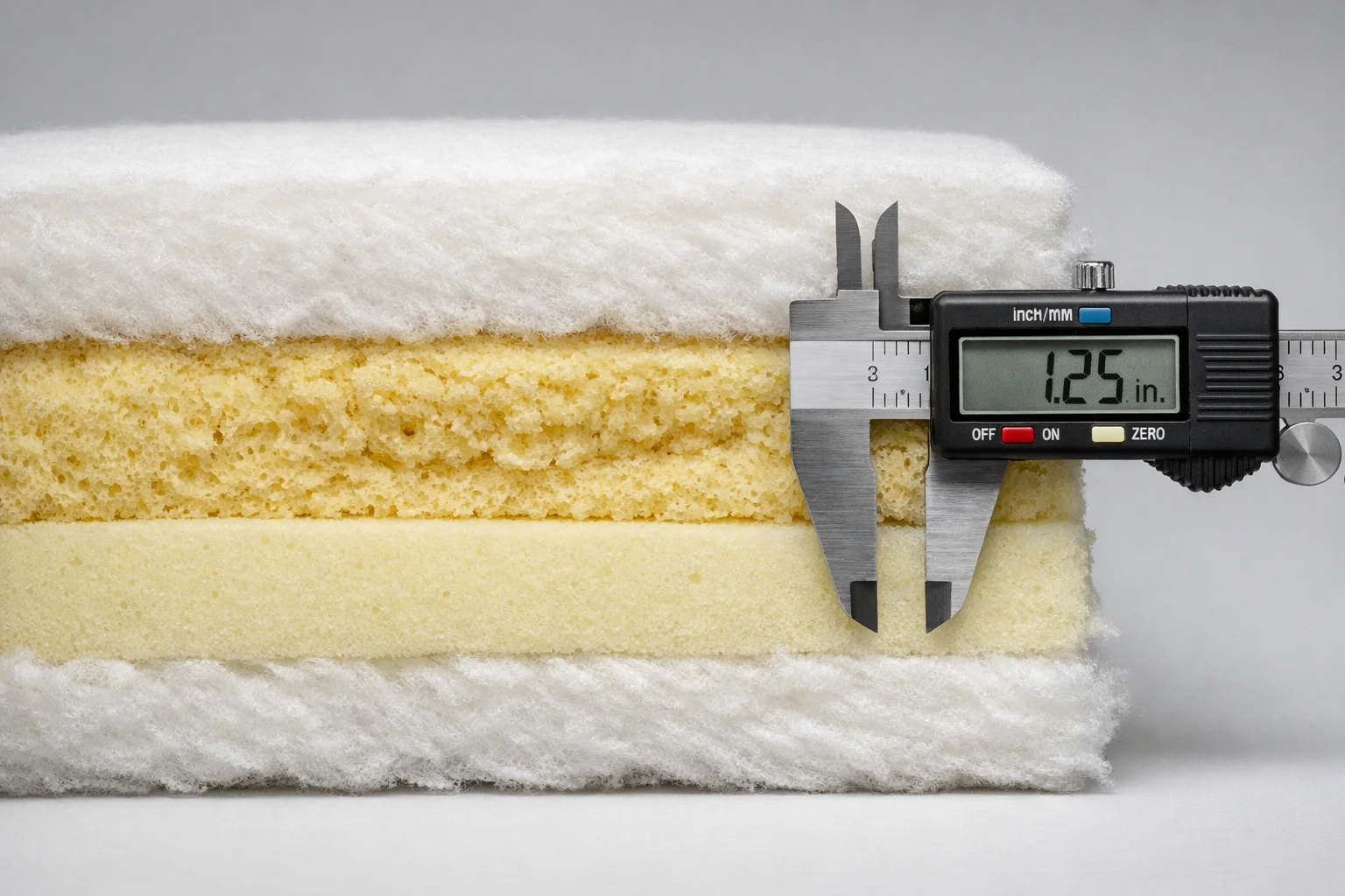 Cutaway cross-section of a sofa cushion showing compressed foam cells and permanent sag measured with calipers