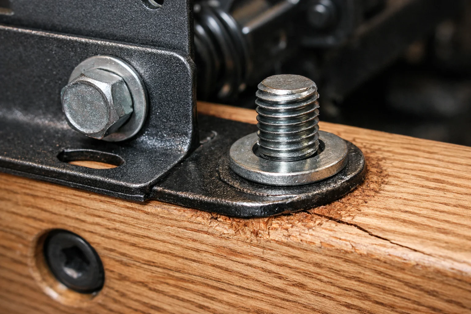 Close-up of a recliner chassis mounting bolt in wood showing loosening and shear stress along the grain