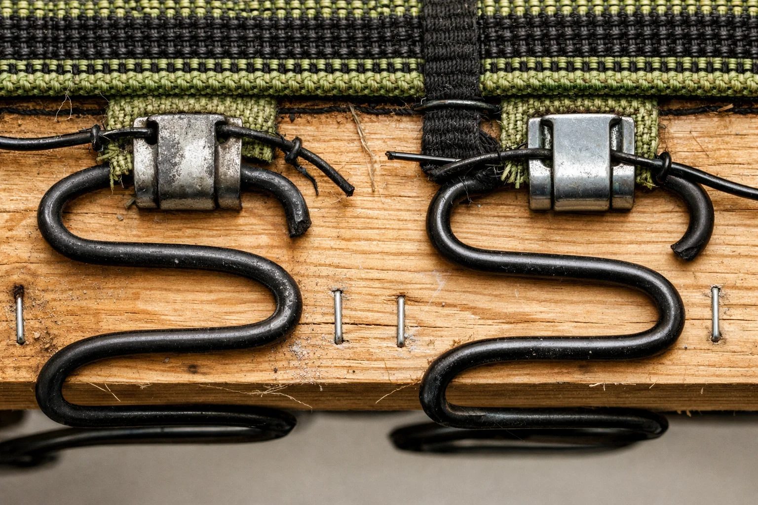 Underside close-up of sinuous spring suspension showing one bay with a fatigued spring and loosened clip